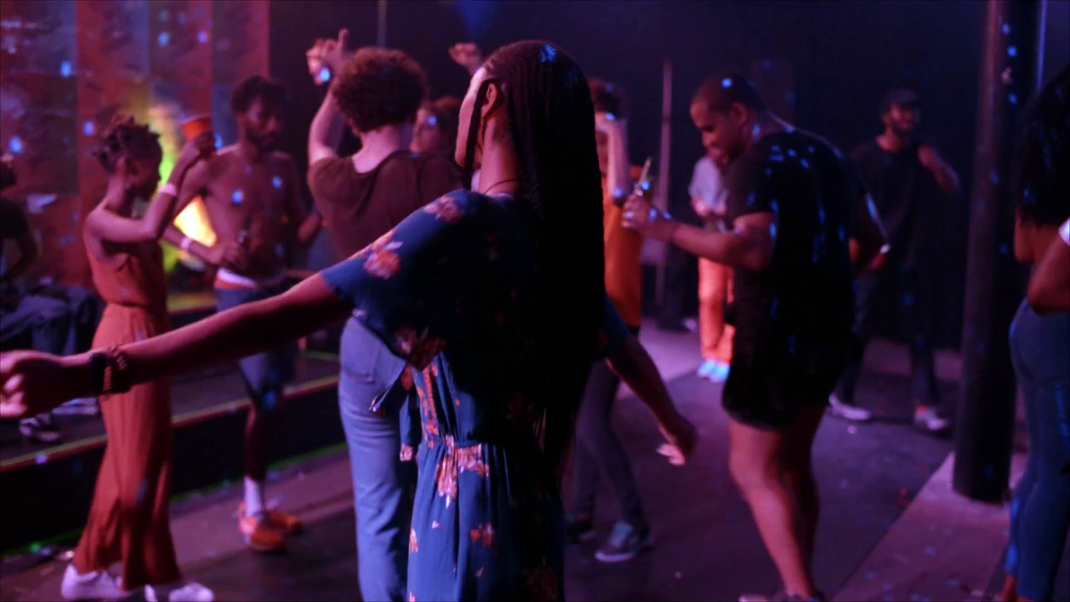 A woman with her back facing the camera dancing in a nightclub.