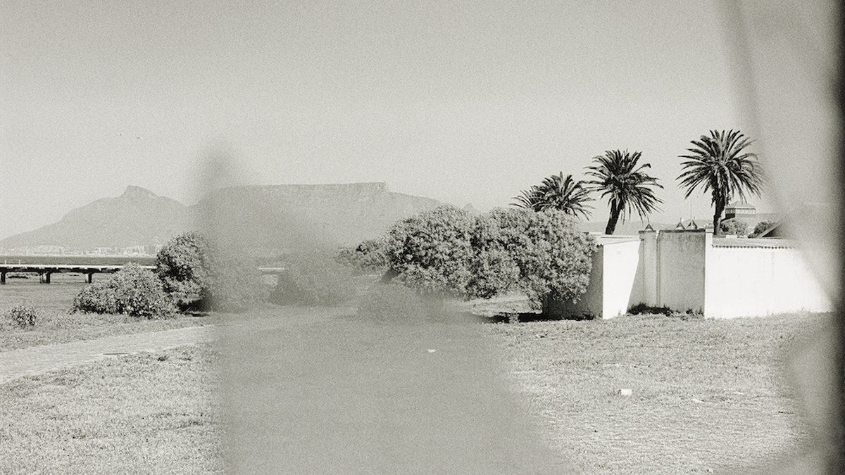 A silver gelatine photograph taken in South Africa, depicting a white house with Table Mountain in the backdrop.
