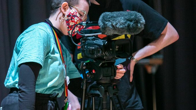 Two people examine a film camera.