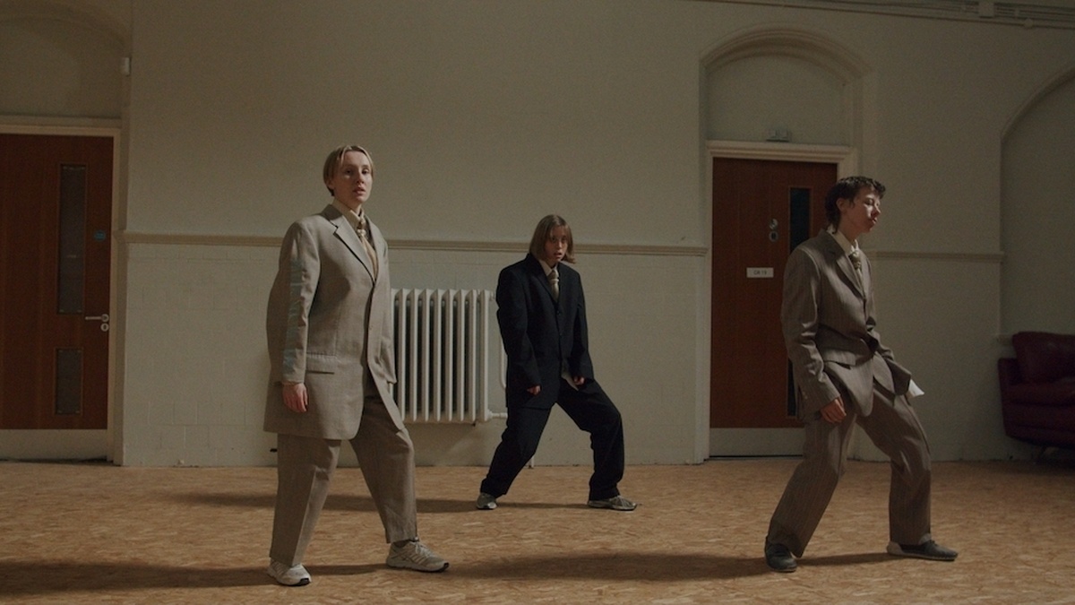 Three people dancing in unison wearing a suit and tie.