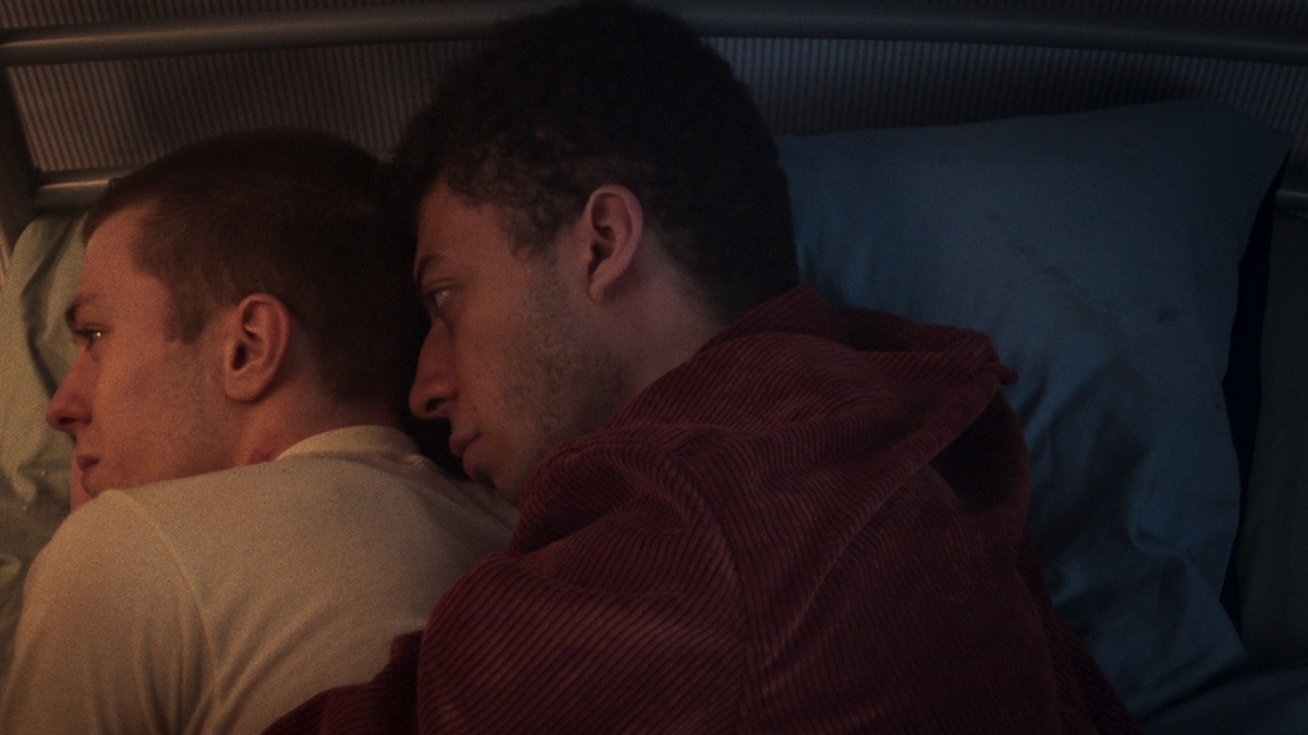 A young man hugs his boyfriend in bed in a comforting manner.