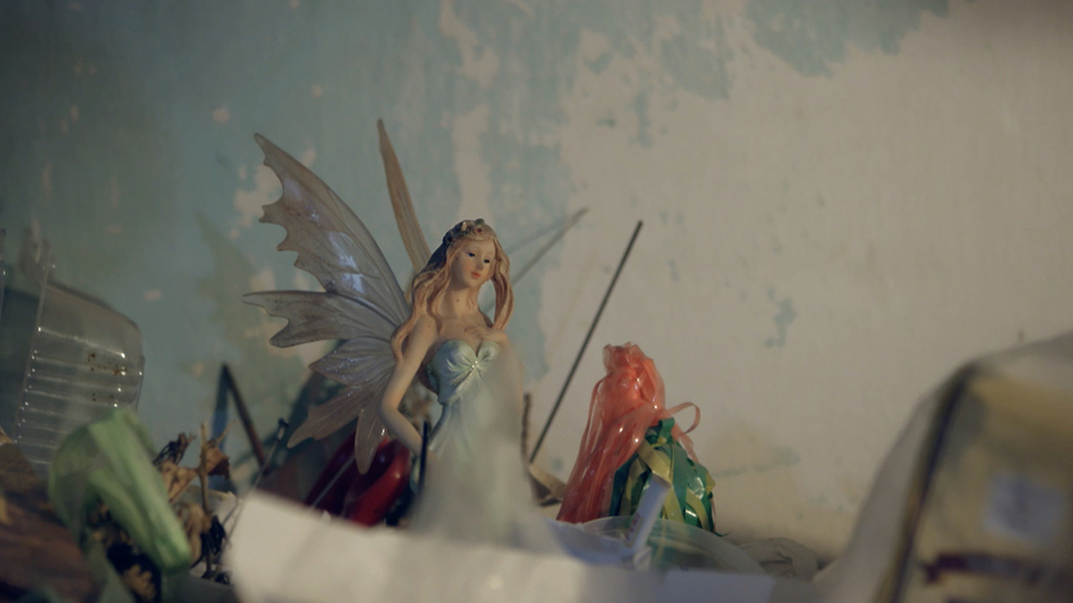 A model fairy stands upon a pile of rubbish.