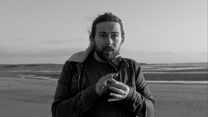 A man has 2 fingers pinched, connected with another 2 fingers in his other hand, in sign language this means connected.