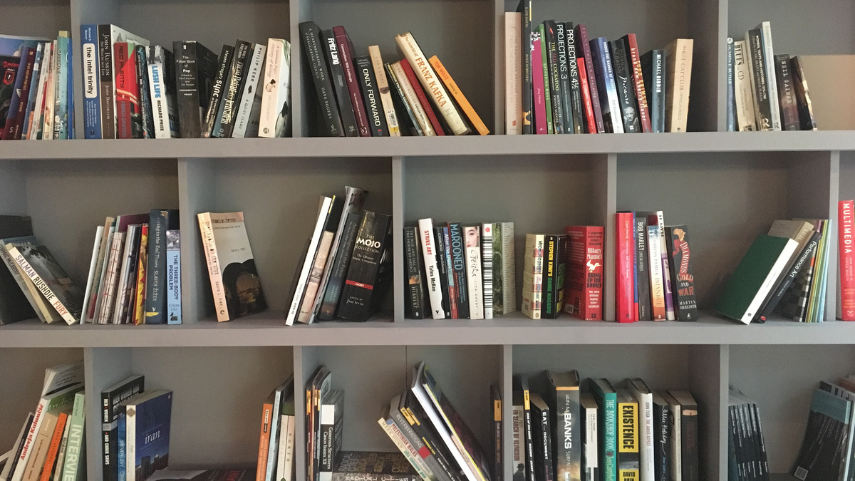 A selection of books spread out over three large grey shelves.